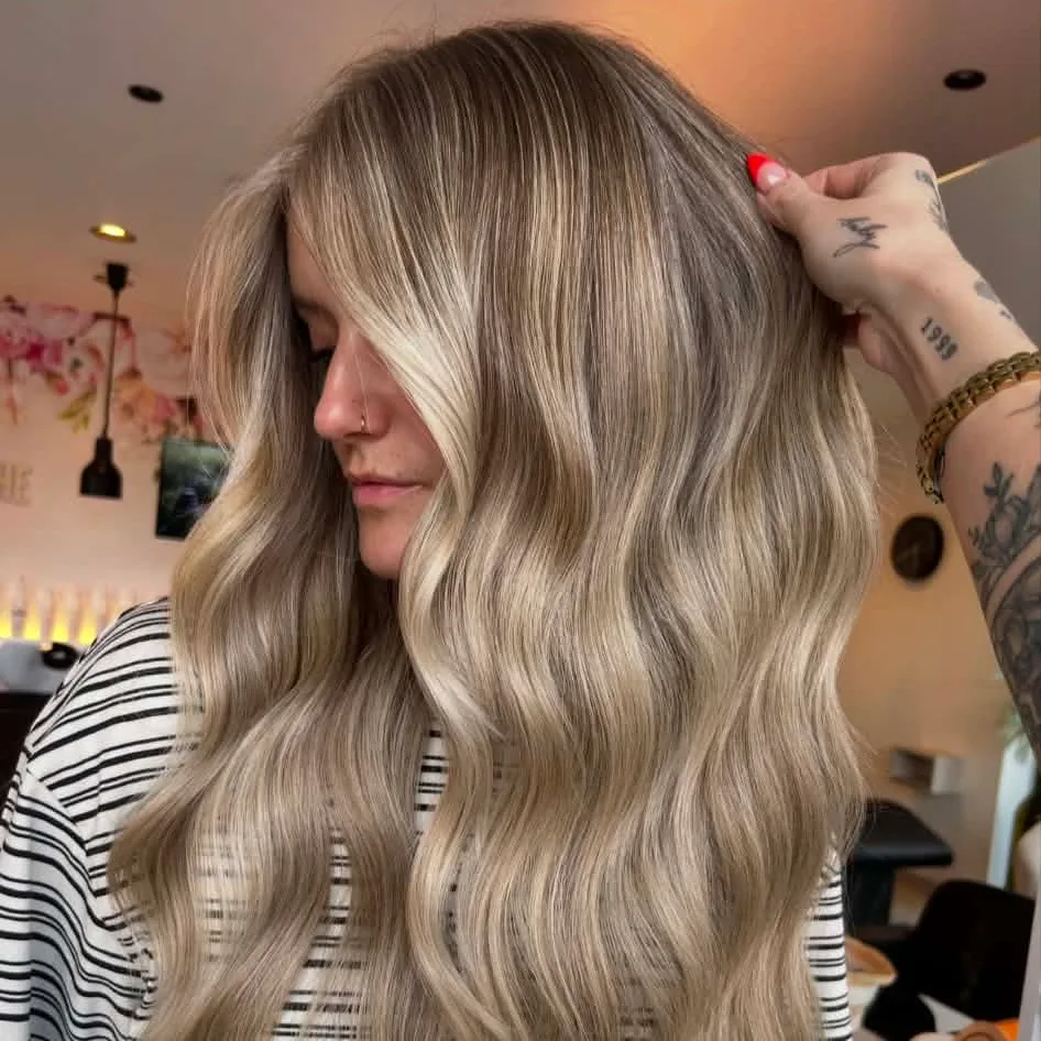 Lang blond haar met een balayage, opzij gedragen, in het salon